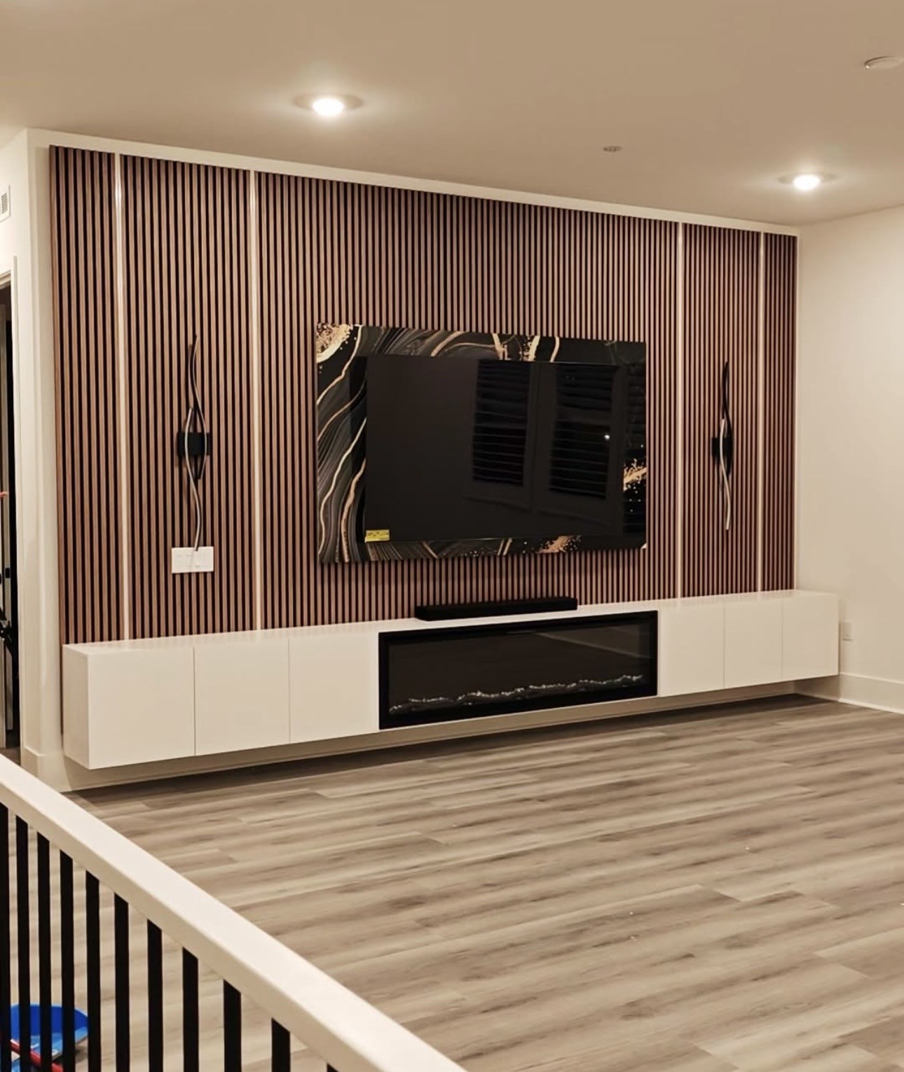 Custom media wall with a mounted TV, electric fireplace, and wood slats in a Kansas City home