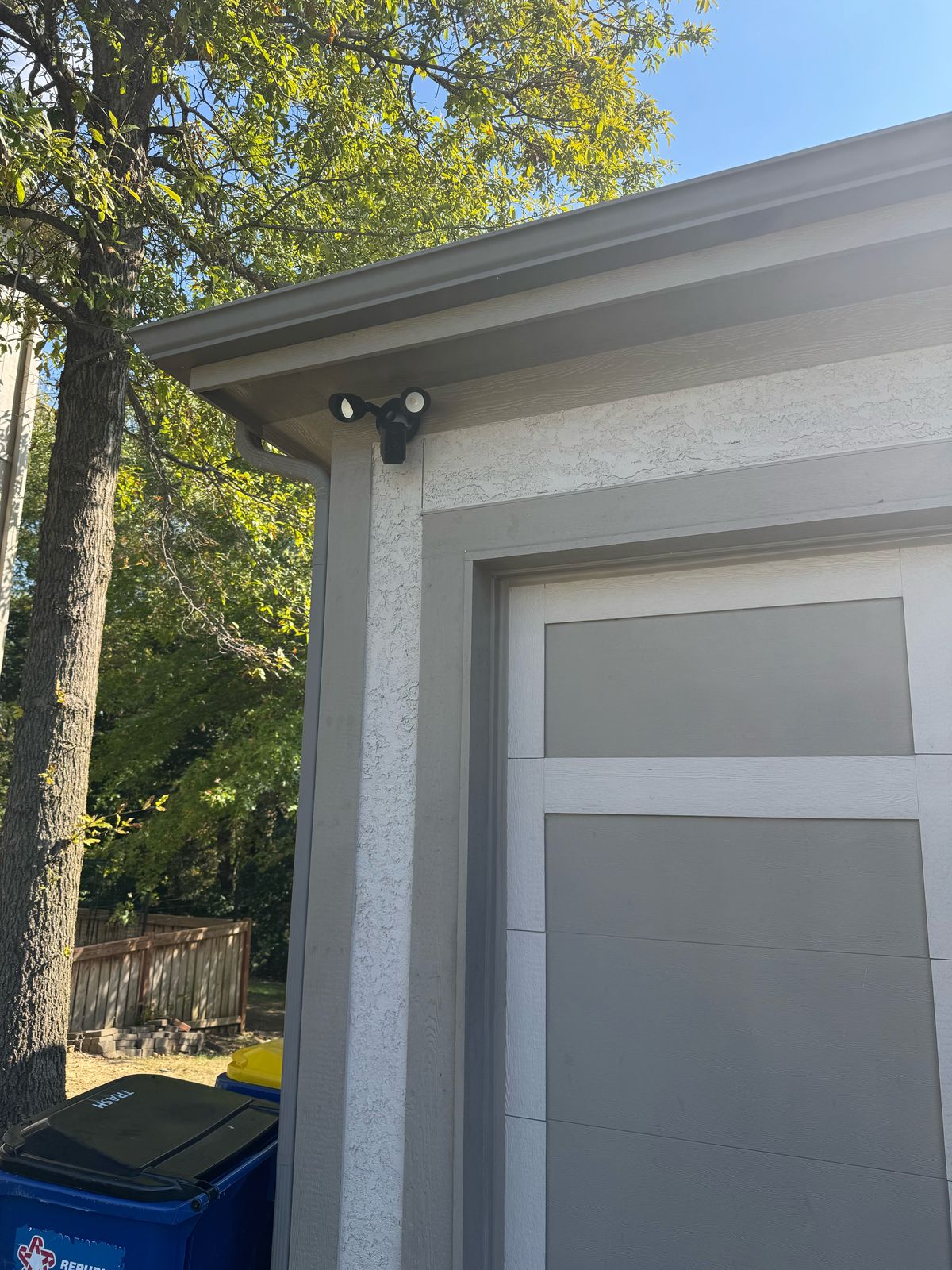 Ring floodlight camera mounted under the soffit above a garage door in the Kansas City area.